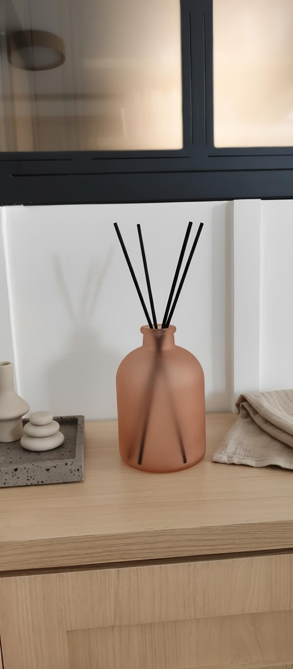 Vaso decorativo de vidro rosa fosco com design minimalista sobre aparador de madeira