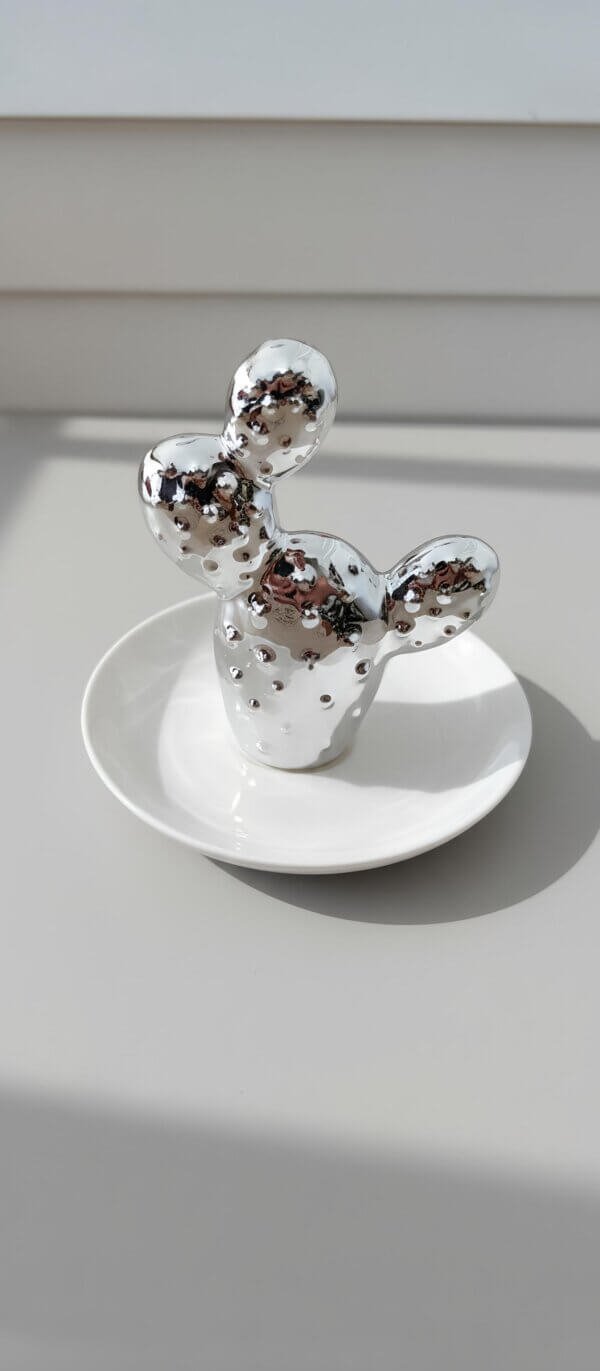 Porta-jóias mini cacto prata em cerâmica decorativa sobre prato com luz natural em ambiente moderno